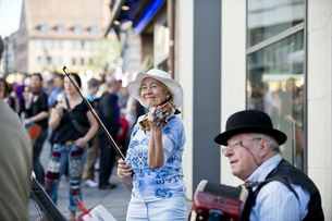 Straßenmusiker in der Fußgängerzone, von Menschen umringt
